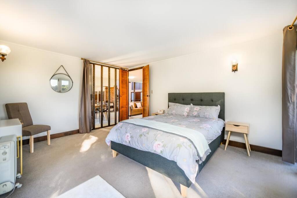 ein Schlafzimmer mit einem großen Bett und einem Fenster in der Unterkunft Pukekohe Farm House 5min to Town Centre in Buckland