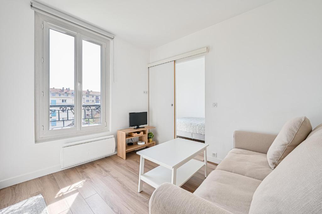 - un salon blanc avec un canapé et une fenêtre dans l'établissement Appartement cosy rénové, proche métro Paris, à Maisons-Alfort