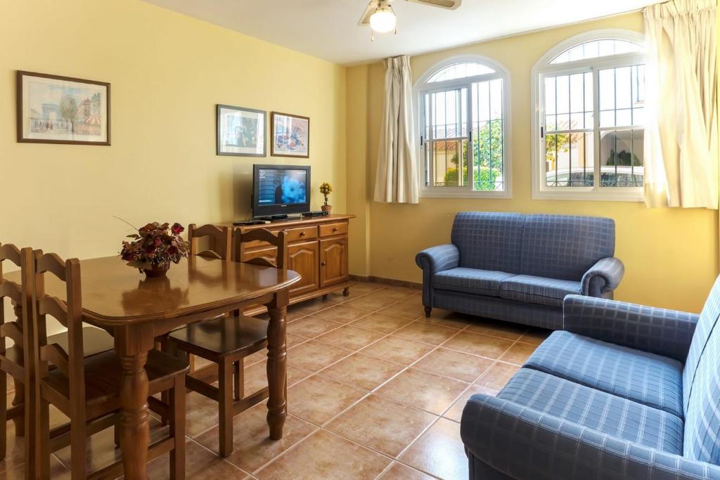 a living room with a table and a couch and a tv at Apartamentos La Casa del Barrio in Maro