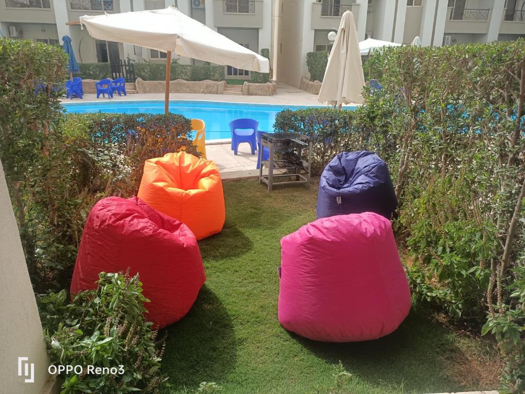 cuatro bolsas de frijol sentadas en el césped cerca de una piscina en Chalet at Lasirena Mini Egypt Resort Ein Elsokhna Families Only, en Ain Sokhna