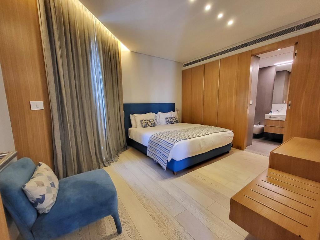 een slaapkamer met een bed en een stoel in een kamer bij Monot Suites in Beiroet