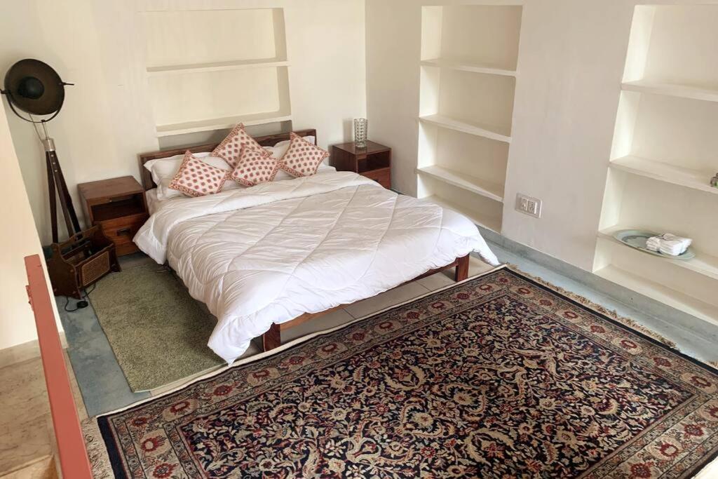 a bedroom with a bed with pillows and a rug at One Bedroom in C-Scheme, Jaipur in Jaipur