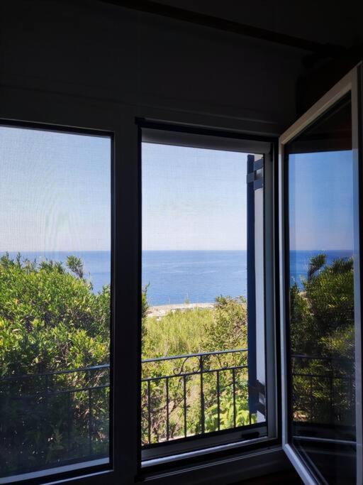 a room with three windows looking out at the ocean at Μπλέ σπίτι in Karavostamo