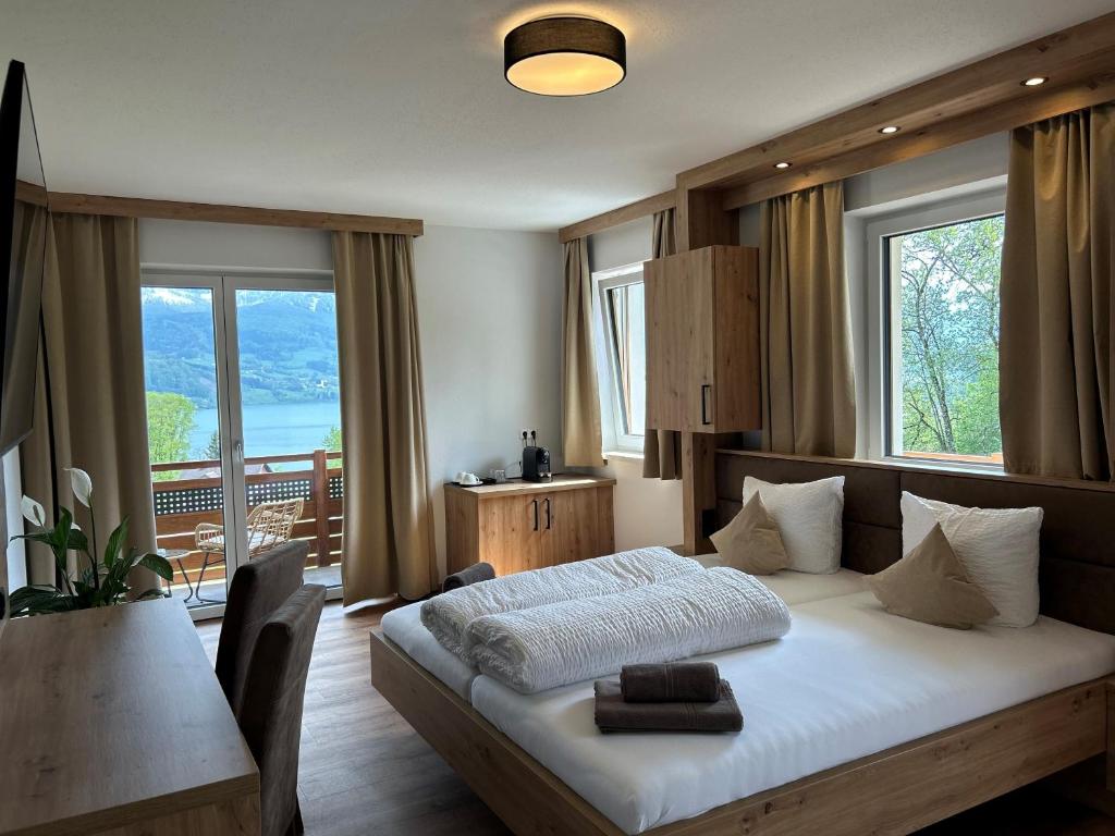 una camera da letto con un letto, un tavolo e finestre di Gasthof Steinbichler a Nussdorf am Attersee