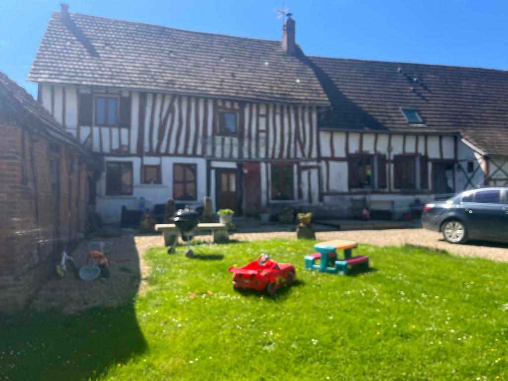 a house with a yard with a toy train in the grass at Maison en Colombage in Tilly