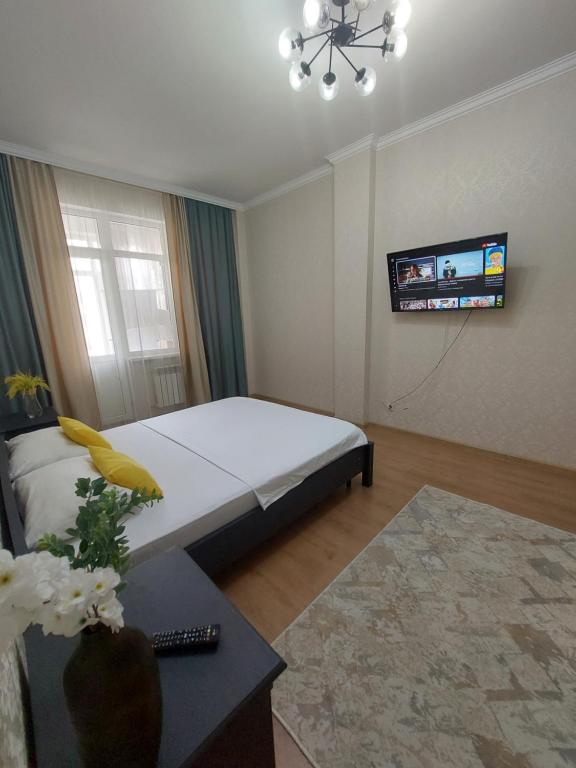 a bedroom with a bed and a tv on the wall at Expo new life in Taldykolʼ