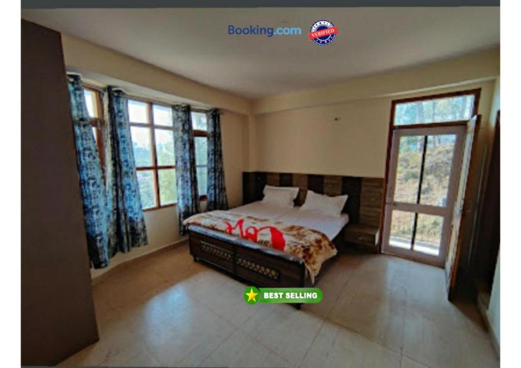 ein Schlafzimmer mit einem Bett in einem Zimmer mit Fenstern in der Unterkunft Hotel Prithvi Haridwar - Excellent Stay with Family, Parking Facilities in Haridwar
