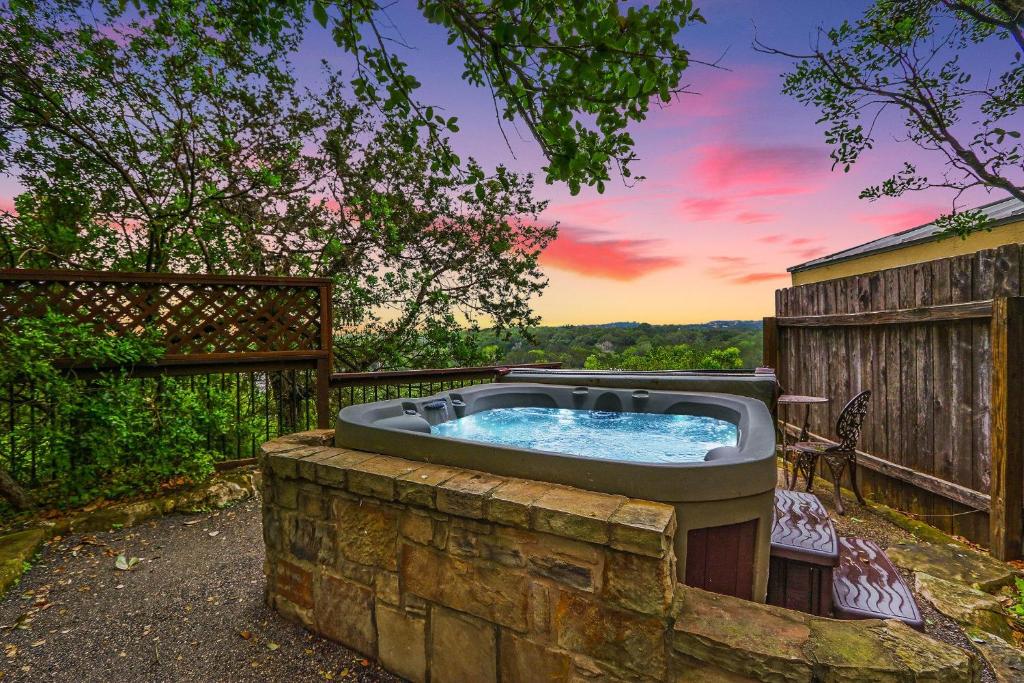 a hot tub in a stone wall with a sunset at Clutter Falls Retreat - Guest House in New Braunfels