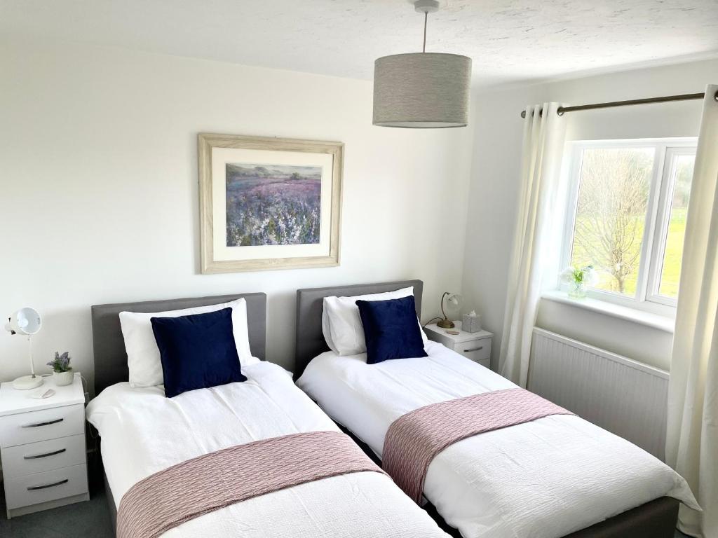 two beds in a room with white and blue at Comfortable and Spacious Superb Holiday Home in Llanelli, Dog Friendly in Llanelli