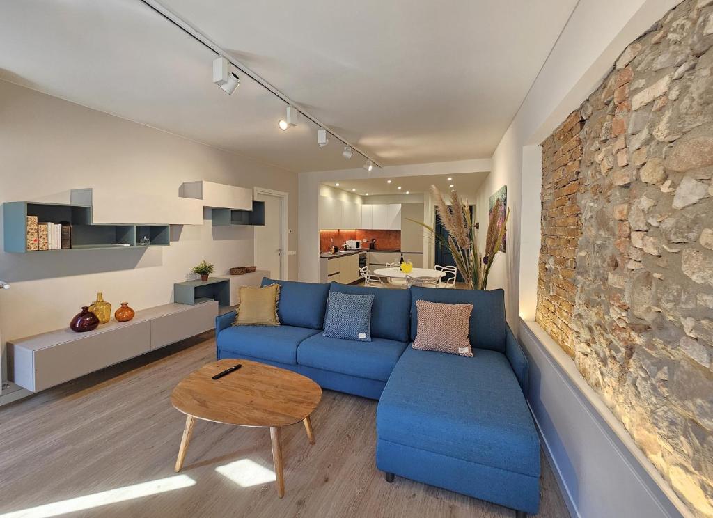 Una sala de estar con un sofá azul y una pared de piedra. en La Piazzuola Salo', en Saló