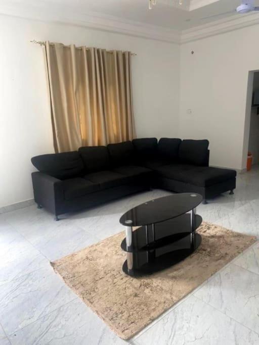 a living room with a black couch and a stool at 3 Bedroom Apartment in Brusubi in Jamisa