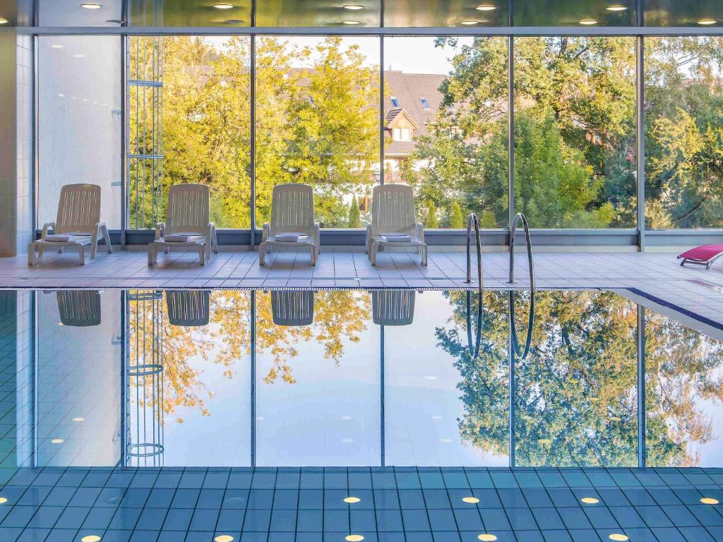 a pool with chairs and trees in a building at Mercure Karpacz Skalny in Karpacz