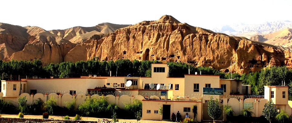 a building with a mountain in the background at Noorband Qalla Hotel,Bamyan 
