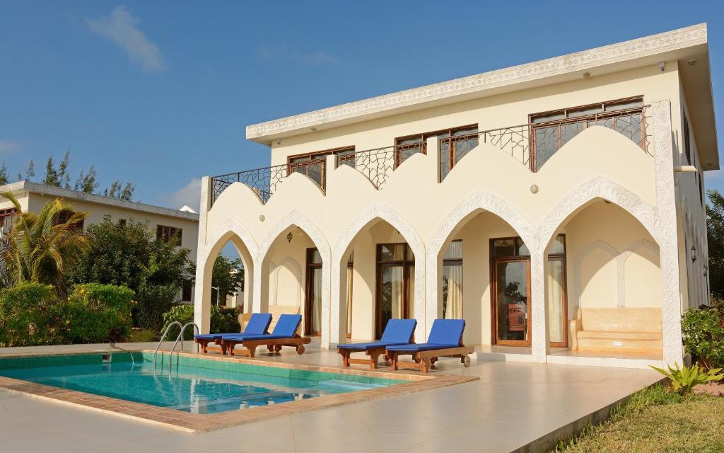 a villa with a swimming pool and blue chairs at Serenity Luxury Villas in Paje