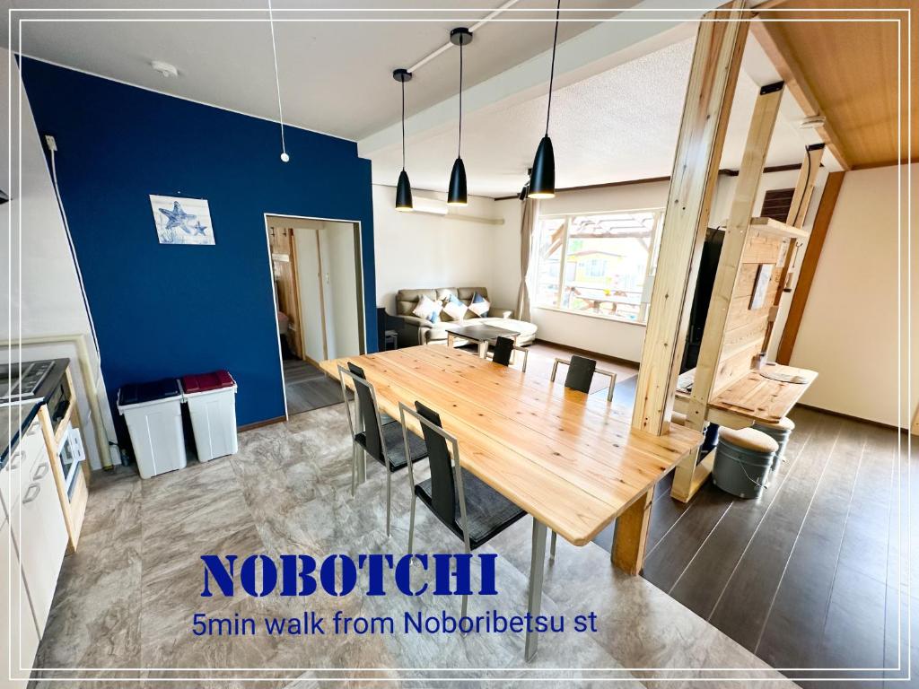 uma sala de jantar com uma mesa de madeira e uma parede azul em Nobotchi のぼっち 5min walk to Noboribetsu st em Noboribetsu