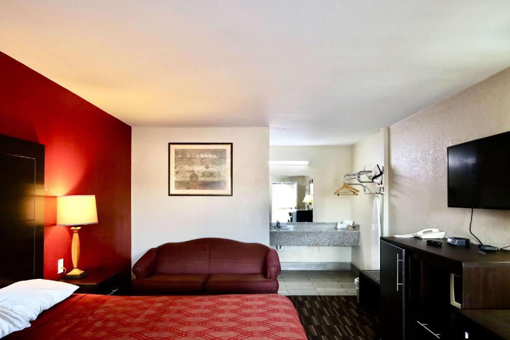 a hotel room with a bed with a red wall at Rodeway Inn in Pauls Valley
