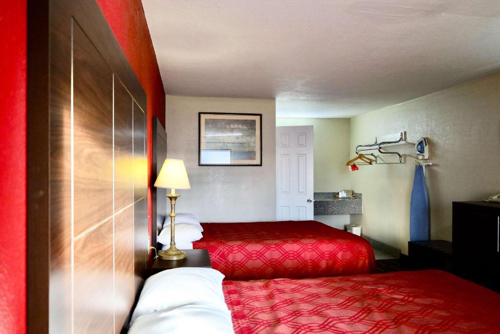 a hotel room with a red bed in a room at Rodeway Inn in Pauls Valley