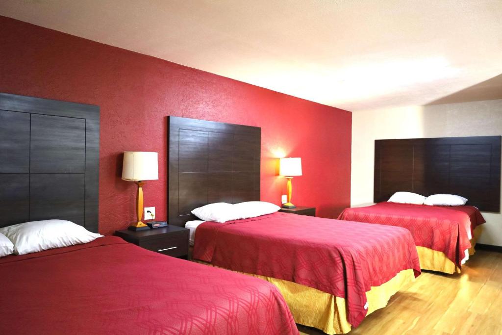 a hotel room with two beds with red walls at Rodeway Inn in Pauls Valley
