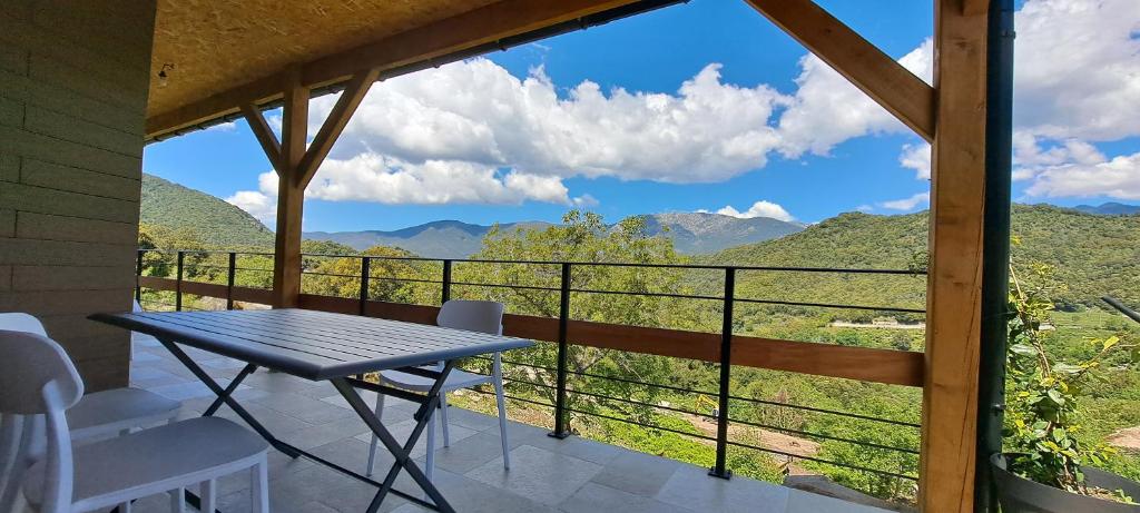 einen Tisch und Stühle auf einem Balkon mit Bergblick in der Unterkunft Maison maquis corse in Zicavo