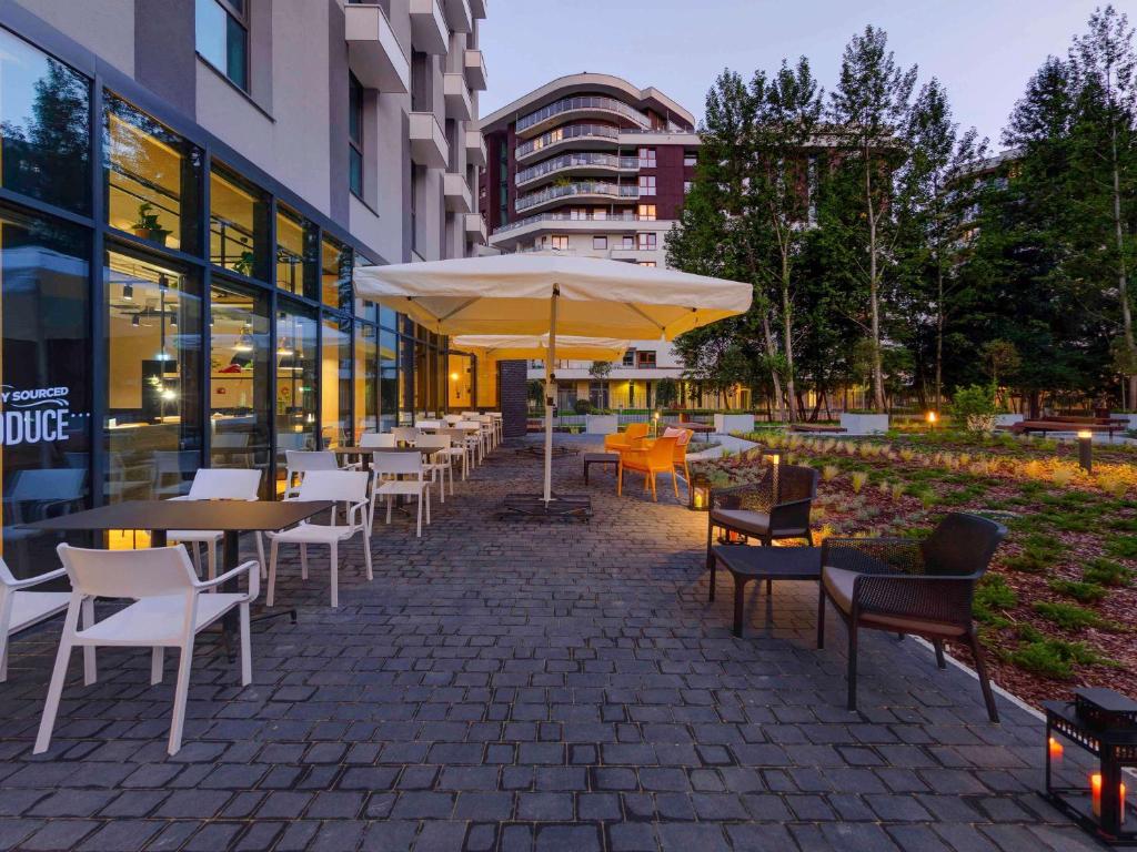 a patio with tables and chairs and an umbrella at ibis Styles Kraków Centrum in Krakow