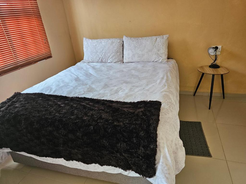 a bedroom with a bed with a black blanket on it at Donsie Guesthouse in Nqutu