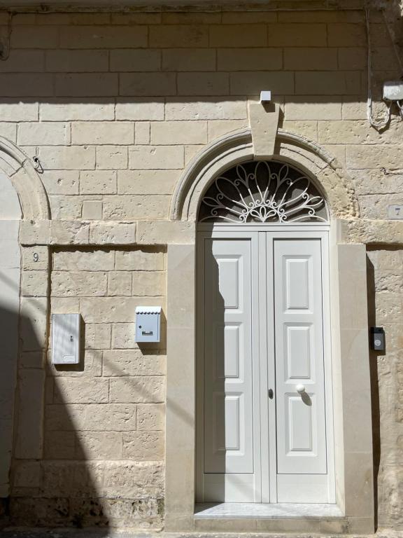 uma porta branca num edifício de pedra com um arco em Casa Caracciolo em Lecce