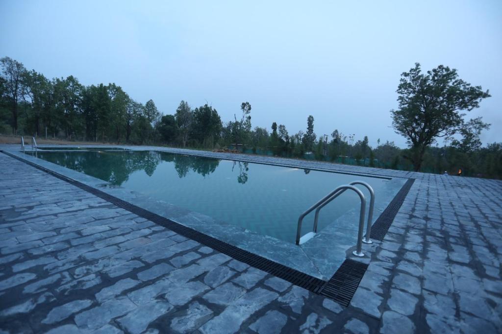 a swimming pool with a metal handrail next to it at Hideaway By Aahma in Rāmnagar