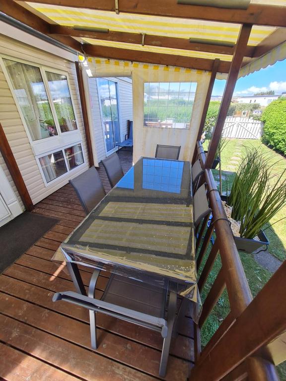 - une table et des chaises sur une terrasse couverte avec une table dans l'établissement GRAND BUNGALOW frond de mer sur la Côte d'Opale, à Camiers