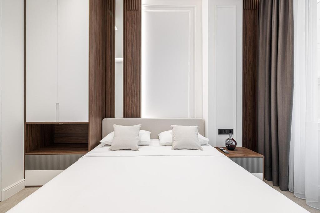 - une chambre avec un grand lit blanc et des oreillers blancs dans l'établissement La victoire, à Beausoleil