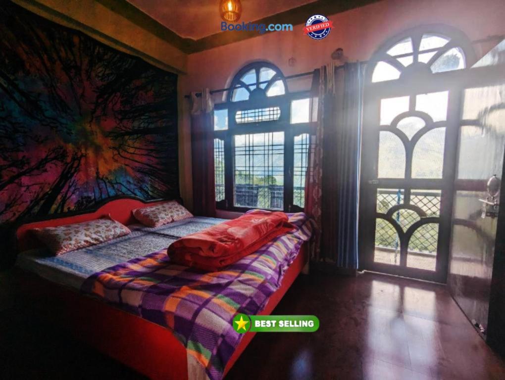 ein Schlafzimmer mit einem Bett in einem Zimmer mit Fenstern in der Unterkunft Goroomgo Mount Kailash Homestay - Natural Landscape & Mountain View in Munsyari