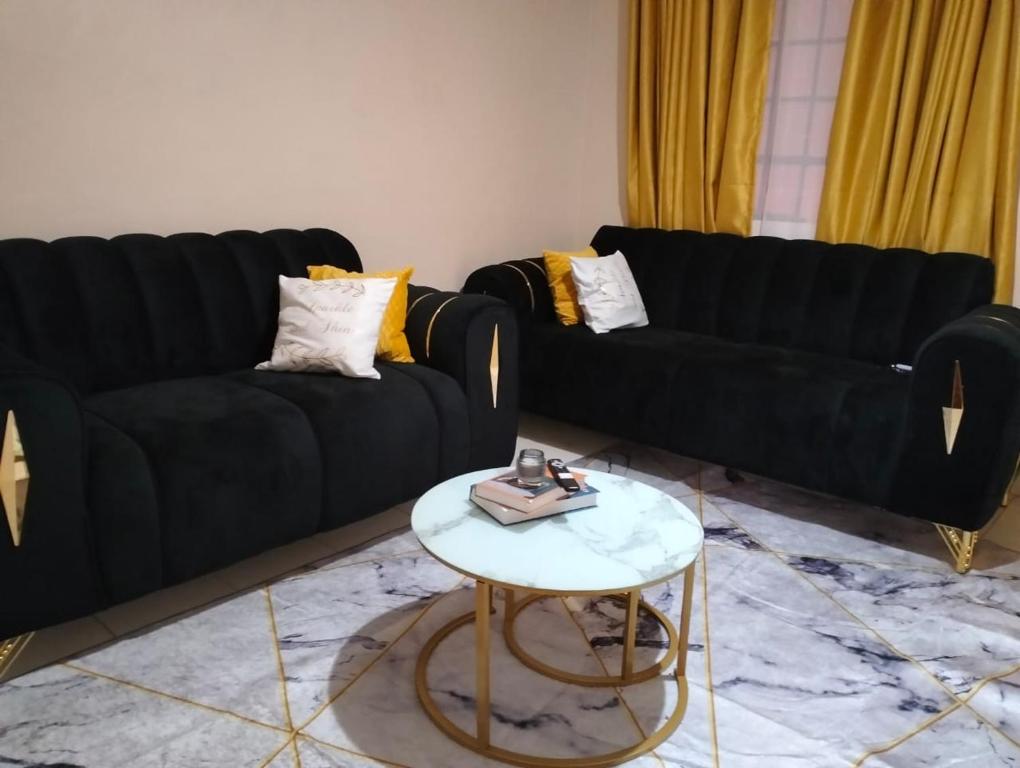 a living room with two black couches and a table at Elite stay in Embu