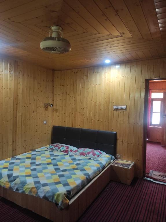 um quarto com uma cama numa parede de madeira em Habib gust house em Tangmarg