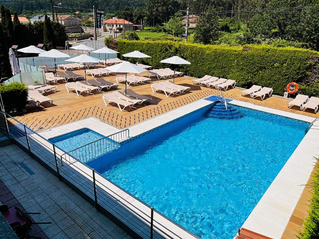 uma vista superior para uma piscina com cadeiras e guarda-sóis em Hotel Susuqui em Sanxenxo