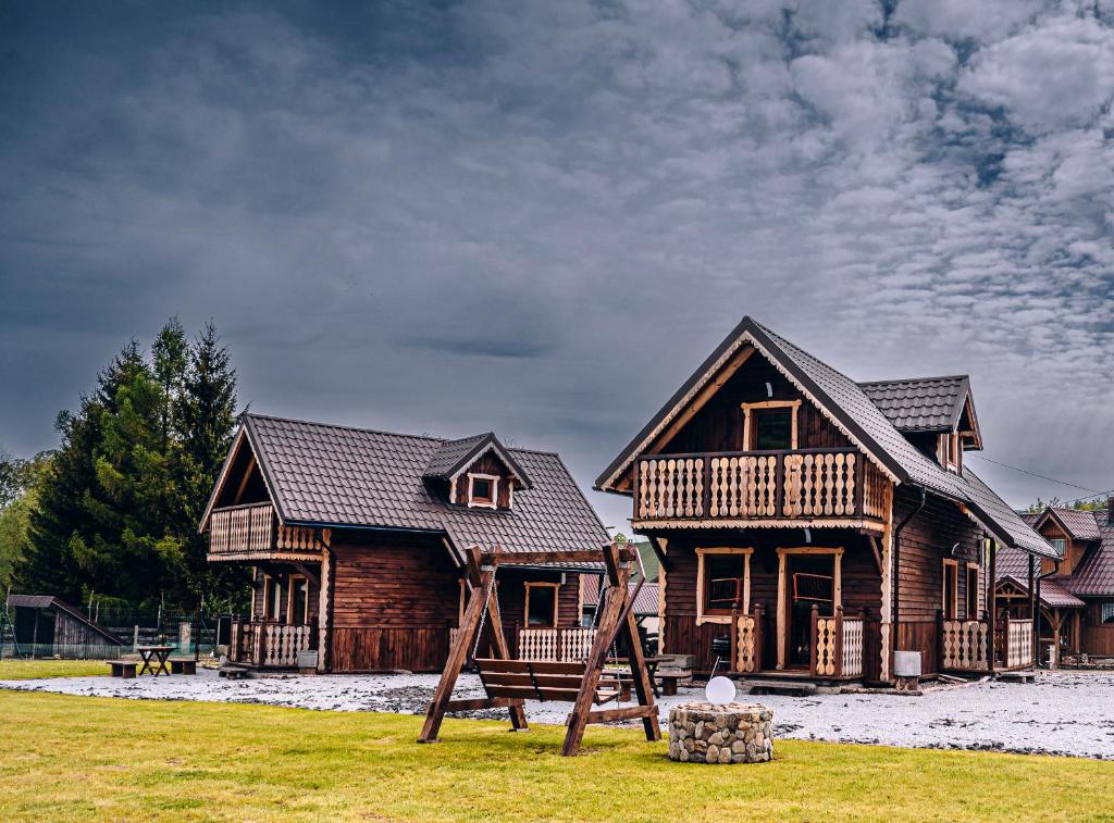 a wooden house with a playground in front of it at Górskie Chatki Krysi i Piotrka Błękitny in Stronie Śląskie