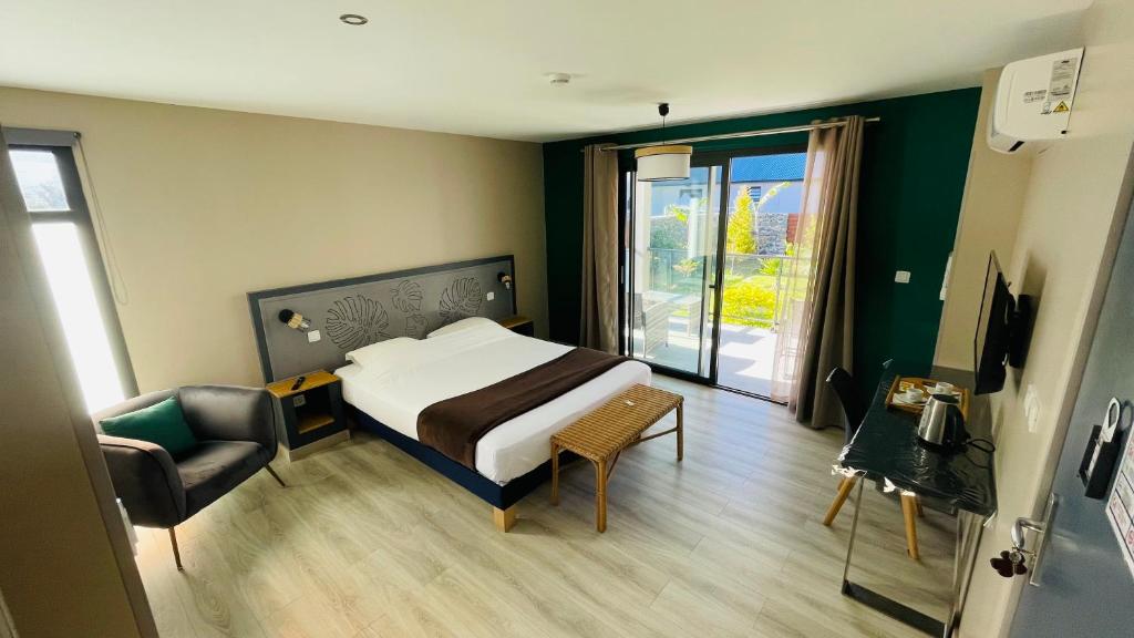 a bedroom with a bed and a chair and a window at La Villa Kazuera in Cilaos