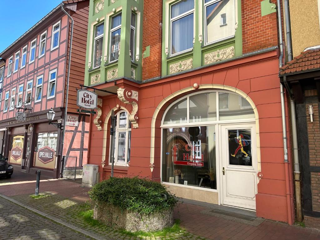 ein rotes Gebäude mit einem Geschäft in einer Stadtstraße in der Unterkunft City Hotel Hameln in Hameln