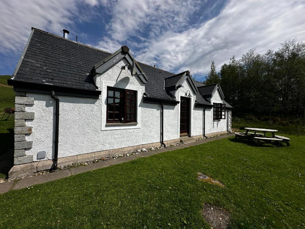 une maison blanche avec une table de pique-nique dans une cour dans l'établissement Farm Cottage with wood-fired Hot Tub, à Taynuilt