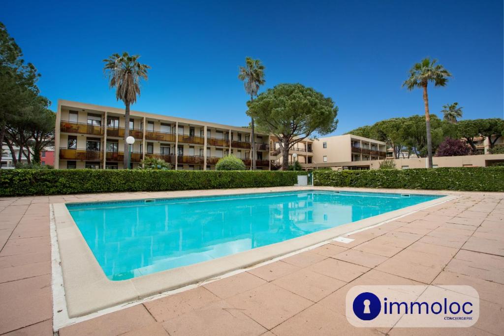 une piscine devant un immeuble avec des palmiers dans l'établissement Air-conditioned studio in Mandelieu with swimming pool, à Mandelieu-la-Napoule