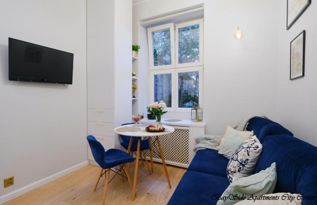 ein Wohnzimmer mit einem blauen Sofa und einem Tisch in der Unterkunft BaySide Apartments Center City in Danzig