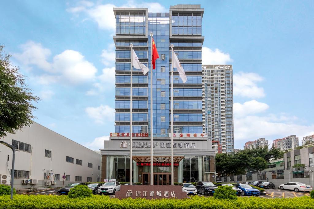 a tall building with two flags in front of it at Jinjiang Metropolo Hotel - Shenzhen Longgang Central City Longcheng Plaza in Longgang