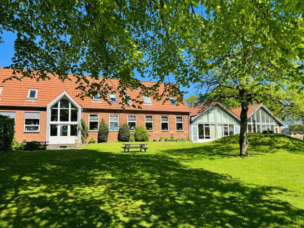 un edificio con un árbol y un banco en el patio en KonceptHotel, en Oksbøl