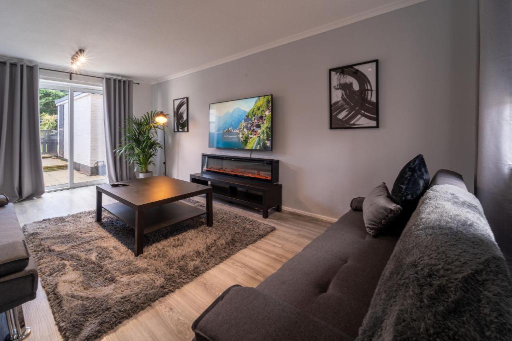 a living room with a couch and a table at Spacious 3 Bed House, 5mins to HS2/ NEC/Airport. in Marston Green
