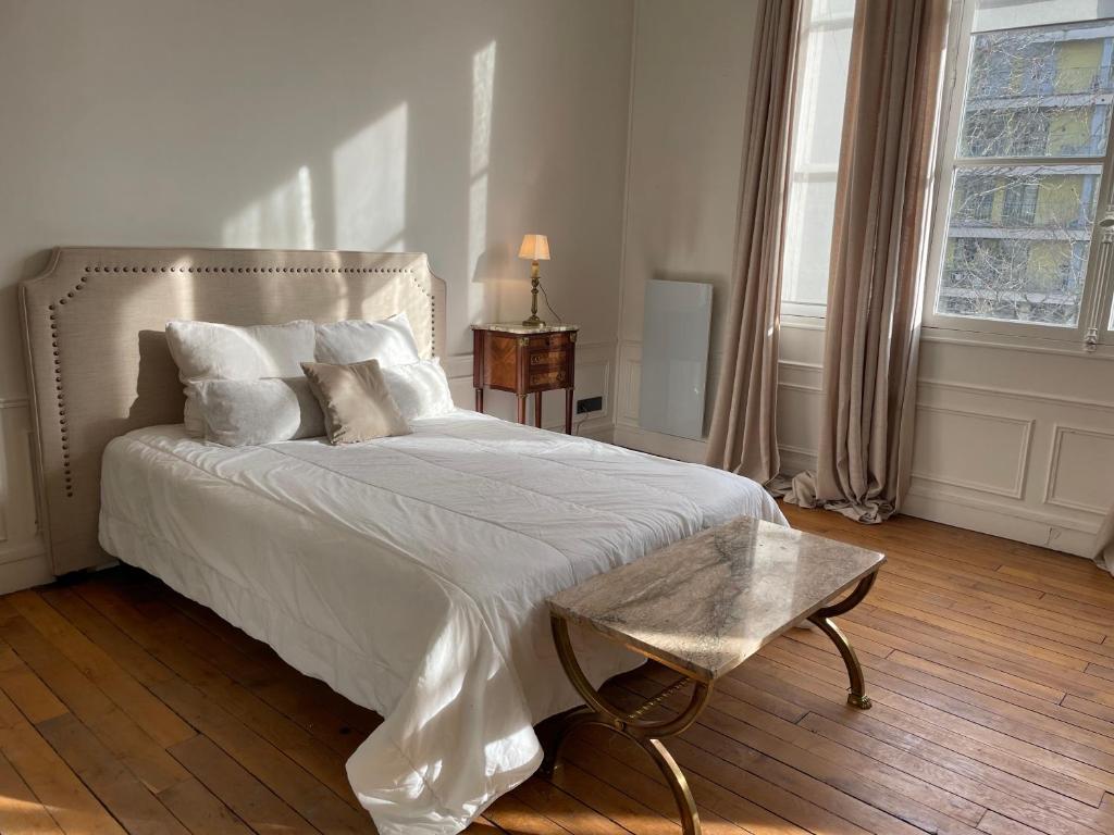 une chambre avec un lit avec des draps blancs et des oreillers dans l'établissement Appartement Paris 7ème Invalides/ Tour Eiffel 1er étage, à Paris
