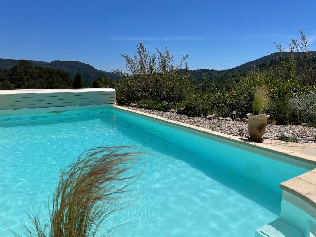 una piscina azul con montañas en el fondo en Les jardins de la Capelière, en Méounes-lès-Montrieux