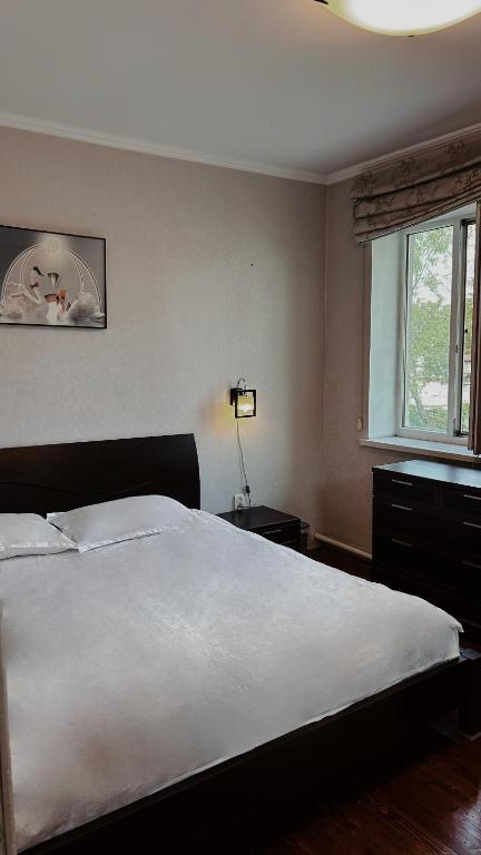 a bedroom with a large white bed and a window at 长城民宿34号院 in Almaty