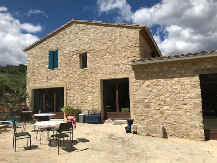 una casa in pietra con un tavolo e sedie di fronte di Maison de campagne La Teranga au coeur du Luberon ad Apt