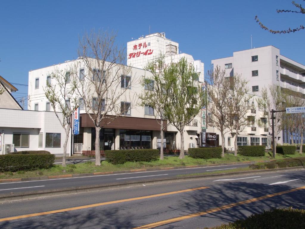 a white building with a sign on it on a street at Tsukuba Daily Inn in Tsukuba