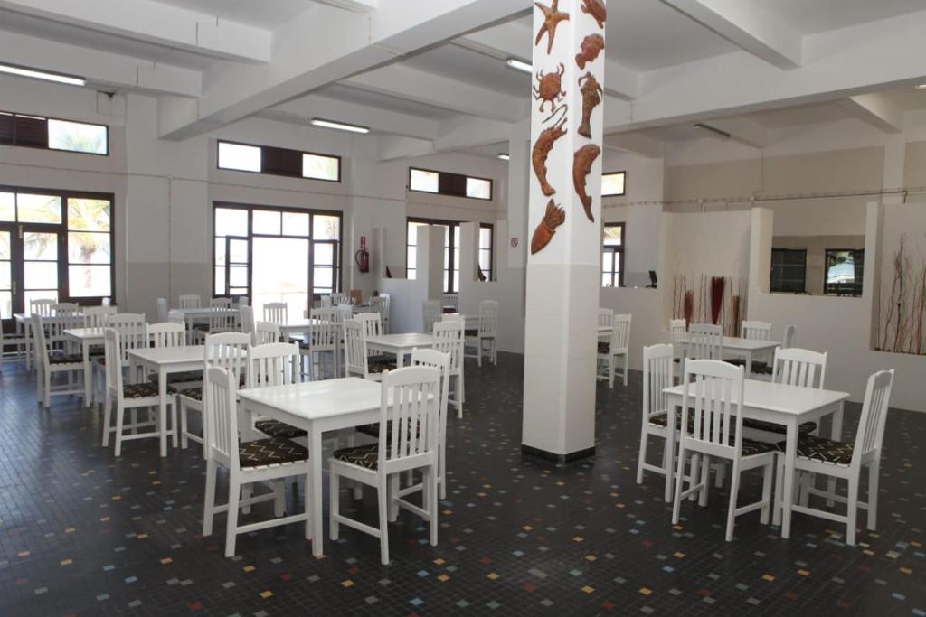 un comedor con mesas blancas y sillas blancas en CFM Sociedade Turística Bilene Resort en Vila Praia Do Bilene