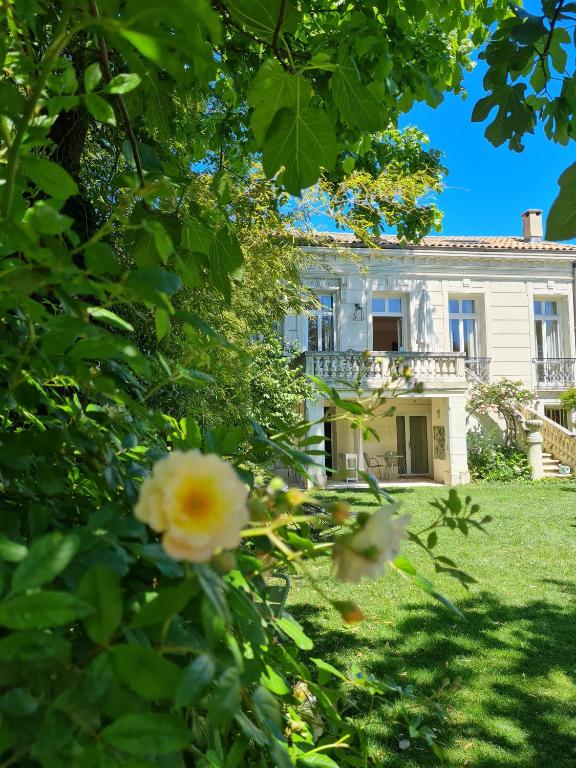 ein großes weißes Haus mit Blumen im Hof in der Unterkunft Villa Aigarden maison d&#39;hôtes in Avignon
