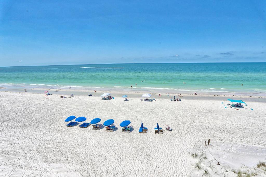 a beach with chairs and umbrellas and the ocean at Villa Madeira 506 - Premier in St. Pete Beach